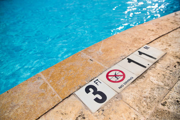 Swimming pool edge with depth warning sign