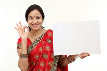 Traditional woman holding a blank billboard and making ok gestur