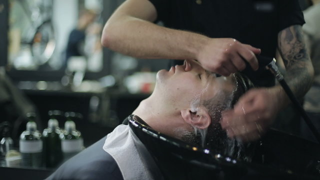 Man Barber Washing Male Hair in a Barbershop
