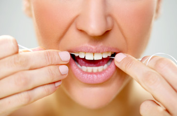 woman cleaning tooth with floss