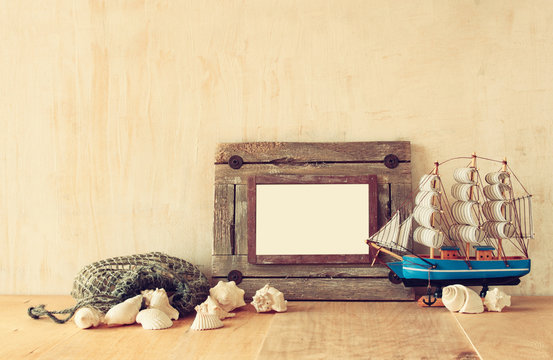 Old nautical wooden frame, boat and natural seashells on wooden 