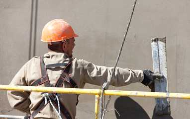 Construction worker plastering multi storey building wall