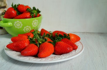 fresh strawberries on a white plate and colorful dish