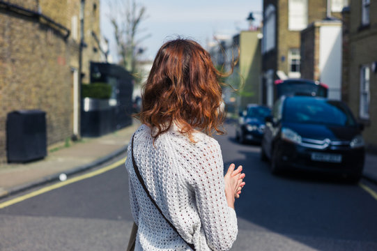 Woman walking in street with parked cars