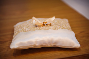 Two wedding gold rings on a cushion for the rings