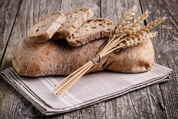 Tasty bread with wheat on wooden background.