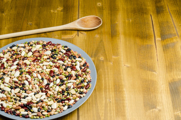 legumes in a dish on wood, with spoon, close up, background