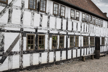 White timbered house, with  a bench and rainbarrel in the old to