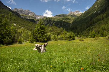 Woman relaxing in a forest clearing in the mountains