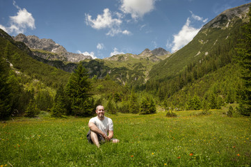 Naklejka na ściany i meble Man relaxing in a forest clearing in the alps