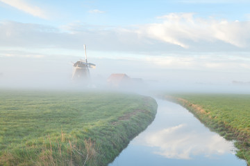 windmill in morning fog by river