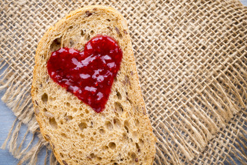 Grain slice of bread with jam heart shape.