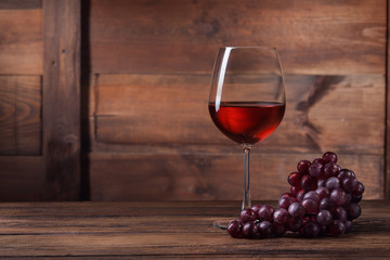 Red wine in glass with grape on wood