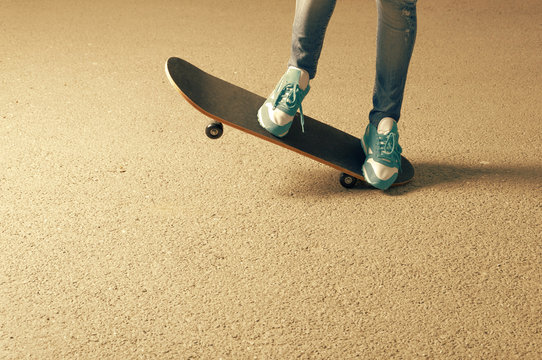Female on skateboard legs and a lot of copyspace on asphalt