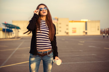 Fototapeta premium Outdoor fashion closeup portrait of nice pretty young hipster woman posing in sunglasses at sunset walks along the streets of the city.