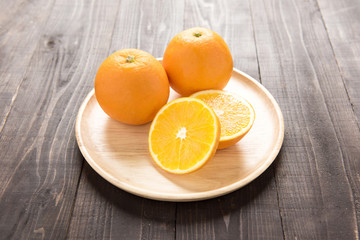 Fresh oranges on wooden dish, fresh fruits on wooden background.