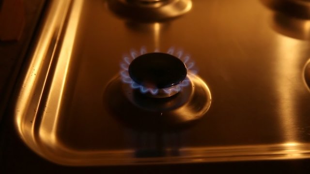 A small gas burner with blue flames in soft light zooming