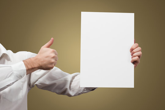 Hands holding a white paper blank isolated on brown background