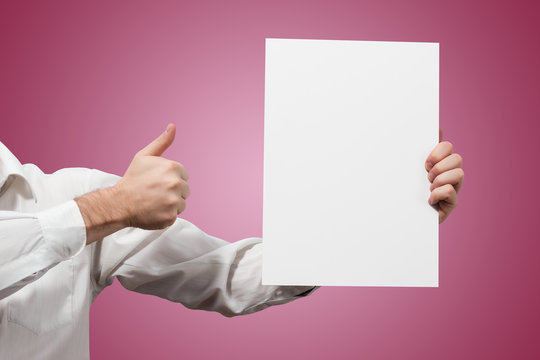 Hands holding a white paper blank isolated on pink background