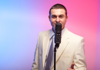 Man in white suit  with microphone. Vivid emotions. Colored back