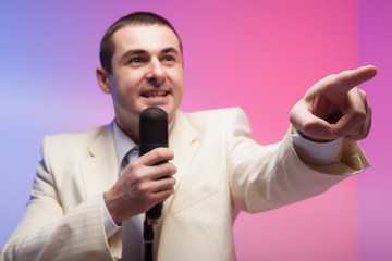 Naklejka premium Man in white suit with microphone. Vivid emotions. Colored back
