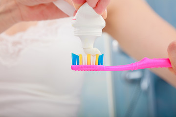 Woman hands putting toothpaste on toothbrush