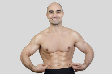 Man smiling showing abs.Man pointing showing six pack abdominal.