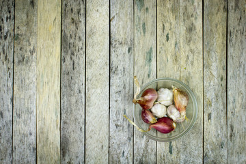 onion and garlic in glass bowl on wood plank