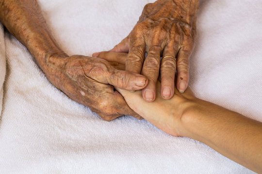 Hand of woman touching senior woman in clinic.