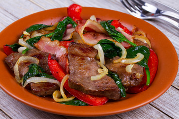 Fried meat, bacon, red paprika pepper and spinach plate