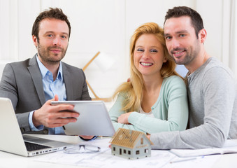 Real estate agent present project on tablet to a young couple