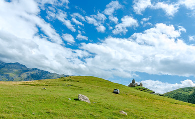 Naklejka premium View on small church in mountains with beautiful clouds