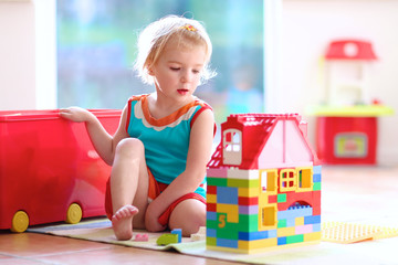 Blonde toddler girl playing with construction blocks