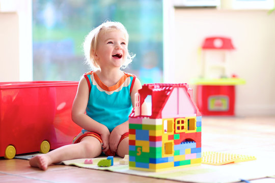 Blonde toddler girl playing with construction blocks