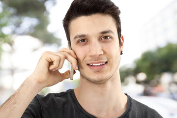 Young man talking mobile phone on street