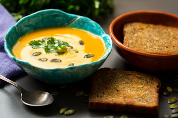 Pumpkin soup in a bowl with seeds and fried bread