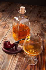 Bottle of brandy and a glass smoking pipe