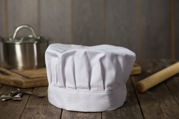Chef hat and wooden spoons on wooden table