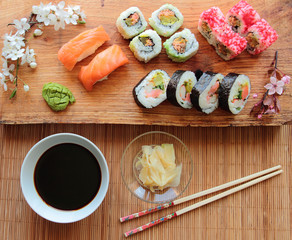 Mix of sushi rolls with soy sauce served on wooden desk