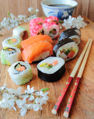 Mix of sushi rolls on wooden desk with chopsticks