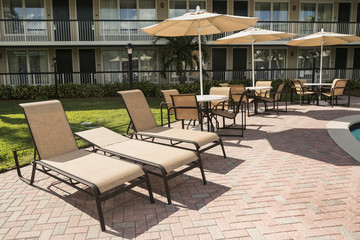 Several chairs with a parasol for sunbathing by the pool.