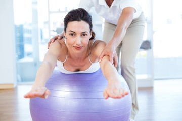 Obraz premium Trainer helping woman on exercise ball