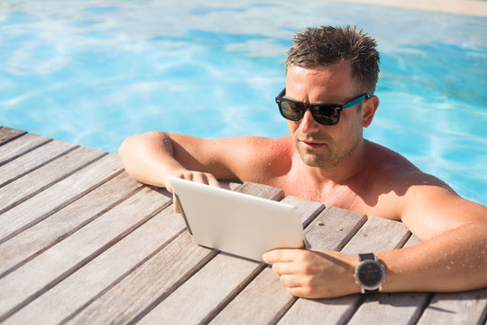 Man using ipad while relaxing in the pool
