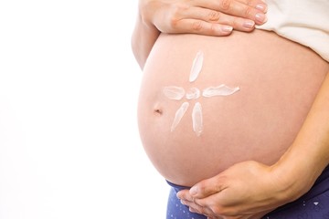 Pregnant woman with cream on bump