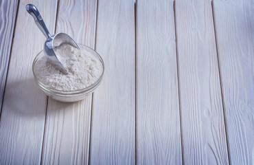bowl with flour and scoop on painted wooden boards