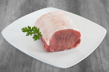 roti de filet de porc cru  sur assiette blanche