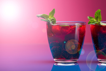 Raspberry and blackberry cocktail with mint garnish. Studio shot