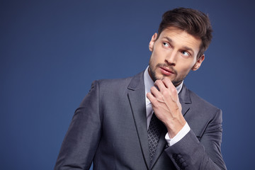 Handsome young business man standing on blue background