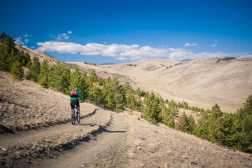 Fototapeta premium The girl on bicycle down a steep hill
