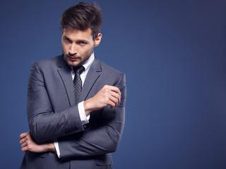 Handsome young business man standing on blue background